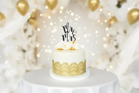 Elegancki tort weselny z napisem "Mr & Mrs" i złotymi zdobieniami. Idealne miejsce, gdzie kupić ozdoby na tort na wyjątkowe okazje.