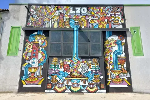 Mural colorato con il nome "LZO Brewery" in alto, raffigurante creature fantastiche, cascate e simboli.