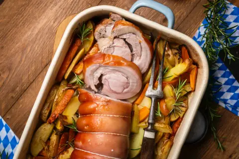 Saftiger **Rollbraten im Backofen** mit knusprigen Kartoffeln und Karotten, garniert mit Rosmarin. Ein Festmahl!