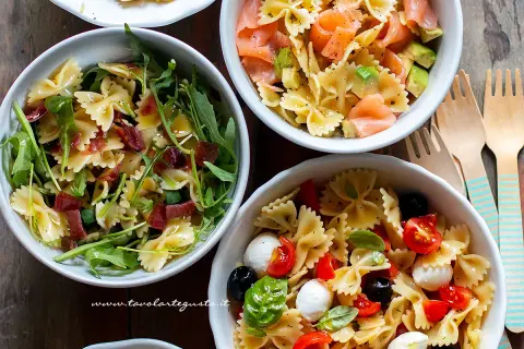 Tre idee per cosa mettere nella pasta fredda: farfalle con rucola e prosciutto, salmone e avocado, o pomodorini, mozzarelline e olive.
