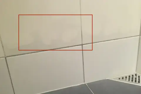 Fuktskada badrum tecken syns som mörka fläckar på kaklet. Vatten har trängt in.