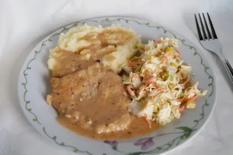 Schab duszony z cebulą w sosie własnym, podany z puree ziemniaczanym i surówką z kapusty. Pyszny, domowy obiad.
