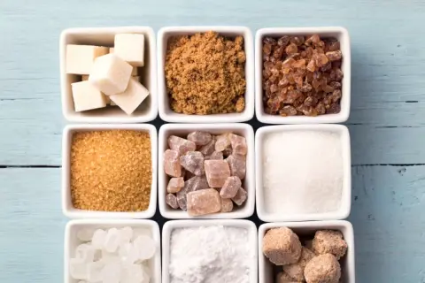 Neuf carrés blancs remplis de différents types de sucre : cubes blancs, cassonade, sucre candi, etc.