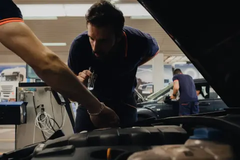 Mecánicos revisan un coche en un taller, asegurándose de que todo esté perfecto cuando se pasa la primera ITV.