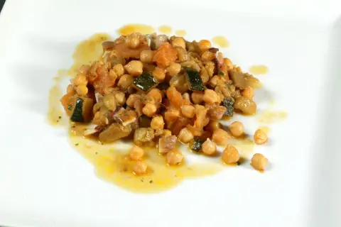 Deliciosos garbanzos con pisto, una mezcla colorida de verduras y legumbres en un plato blanco.