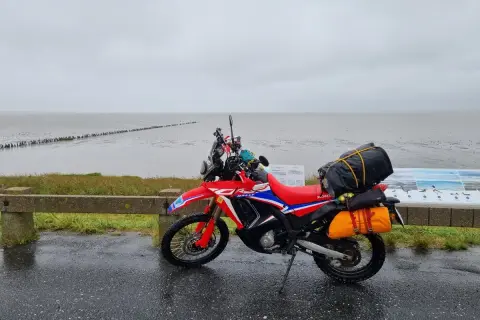 Czerwony motocykl przygotowany na podróż motocyklem nad morze, zapakowany i gotowy do drogi.