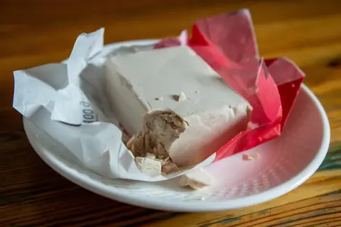 Kostka świeżych drożdży na talerzyku. Zastanawiasz się, czy drożdże można mrozić? Tak, można je zamrozić, by zachować ich świeżość na dłużej.