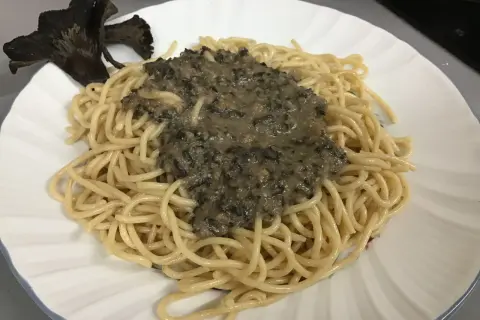 Deliciosa pasta con una cremosa salsa de trompetas de la muerte y un hongo entero como decoración.