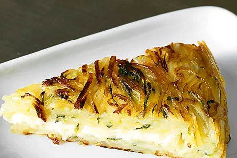 En gyllene potatiskaka i ugn med en krämig fyllning, serverad på en vit tallrik.