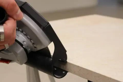 Hand mit Werkzeug schneidet Terrassenplatten. Präzises Arbeiten für die perfekte Verlegung.