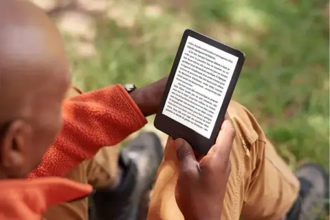 Un homme lit sur sa liseuse, profitant du plein air. Il a peut-être converti des fichiers azw to epub pour une lecture nomade.