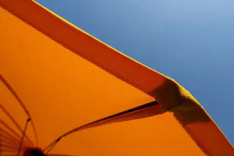Orange Sonnenschirm-Stoff mit Baumwolle für UV-Schutz vor blauem Himmel.