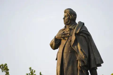 Pomnik Adama Mickiewicza na tle nieba.