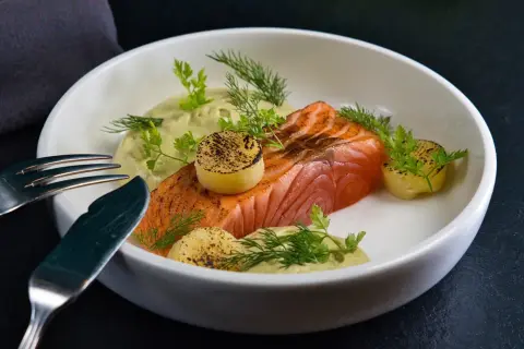 Un délicieux saumon à la toscane, servi avec une sauce crémeuse, des pommes de terre grillées et des herbes fraîches.