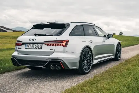 Białe Audi RS6 C8 z pakietem ABT na tle zielonych wzgórz. Widok z tyłu na sportowe detale i felgi.