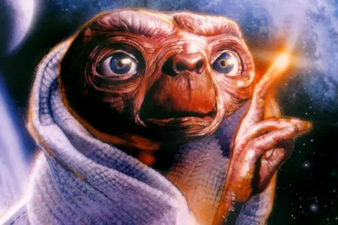 E.T. z filmu o kosmitach lat 80. otulony kocem, z palcem wskazującym w stronę świecącego punktu na tle kosmosu.