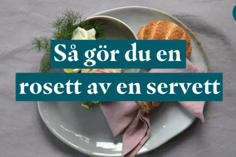 En dukning med en rosett av en servett, blommor och en bulle.