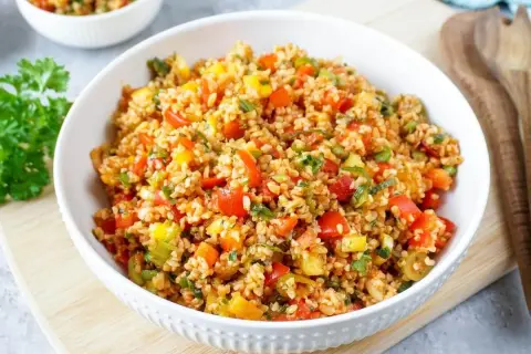 Frischer bulgur salat mit bunten Paprikawürfeln und Kräutern, serviert in einer weißen Schüssel.