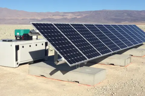 Un impianto fotovoltaico ad isola in un paesaggio arido, con pannelli solari e un'unità di controllo. Le autorizzazioni per questo sistema sono fondamentali per l'energia sostenibile.