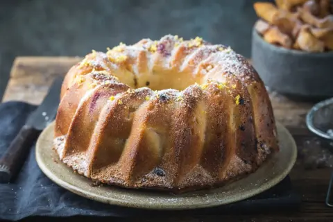 Szybka babka wilgotna, ozdobiona cukrem pudrem i skórką cytrynową, wygląda apetycznie.