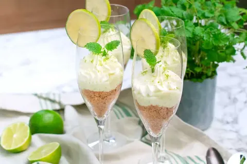 Söta key lime pie i glas, toppad med vispgrädde och lime. En perfekt dessert för sommaren.
