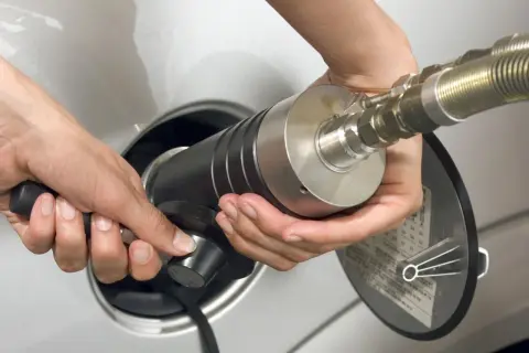 Mani che inseriscono un ugello per il rifornimento di gpl metano in un'auto.