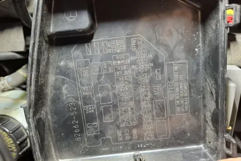 Pokrywa skrzynki bezpieczników w Toyota Yaris 2. Widoczne oznaczenia bezpieczników i ich lokalizacja.