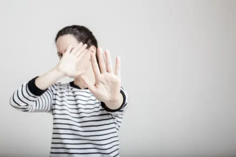 Une femme en pull rayé lève les mains pour se protéger, comme dans un exemple de copyright photo.