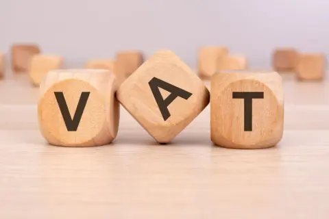 Drewniane kostki z literami V, A, T. Symbolizują fakturę bez VAT, czyli transakcję zwolnioną z podatku.