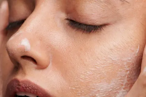 Une femme applique une crème sur son visage. C'est le moment idéal pour savoir quand appliquer crème solaire visage pour une protection optimale.