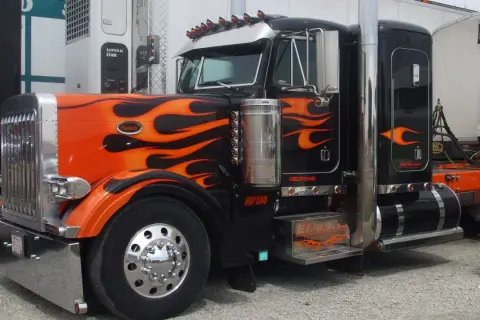 Camion tuning noir et orange avec des flammes, prêt pour la nuit.