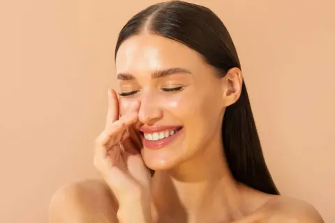 Une femme rayonnante sourit, découvrant les bienfaits du cuivre sur les cheveux. Sa peau lumineuse et ses cheveux brillants témoignent de sa beauté naturelle.