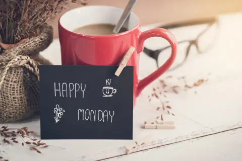 Czerwony kubek kawy, bukiet suszonych traw i tabliczka z napisem "Happy Monday" zapowiadają nowy tydzień.