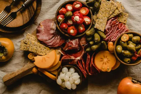 Deska serów i wędlin z owocami kaki, oliwkami i piklami. Idealna na wino aperitif.