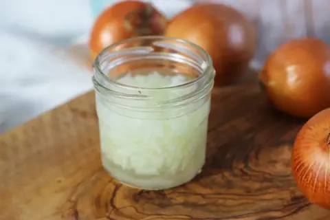 Zwiebelsaft husten: Gehackte Zwiebeln in einem Glas, bereit zur Zubereitung eines natürlichen Heilmittels gegen Husten.
