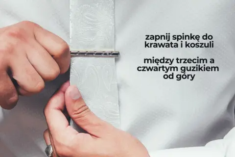 Mężczyzna zapina spinkę do krawata i koszuli między trzecim a czwartym guzikiem od góry. Elegancki sposób na noszenie spinki do krawata.