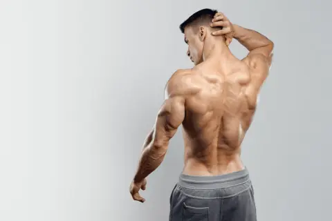 Uomo con muscoli spalle e schiena scolpiti, posa di profilo con mano dietro la nuca.