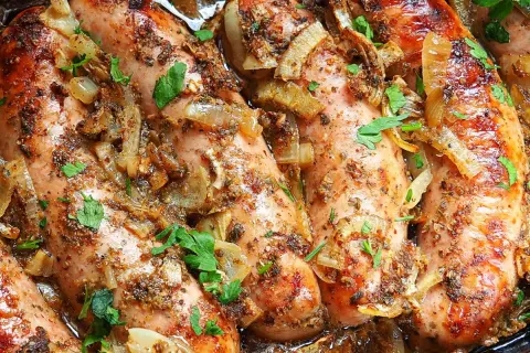Soczysta biała kiełbasa w piwie, duszona z cebulką i ziołami, posypana natką pietruszki.