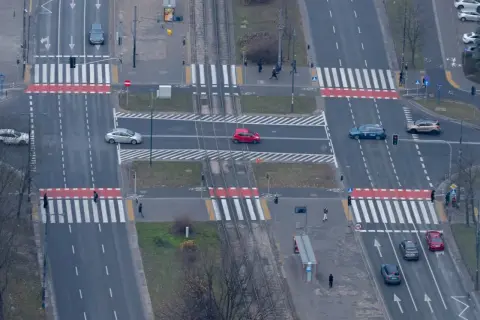 Skrzyżowanie z przejściami dla pieszych. Czerwony samochód jedzie po pasach, zastanawiając się, ile za wyprzedzanie na pasach.