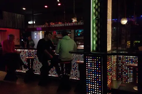 Leute sitzen an einer Bar in Stuttgart, die mit bunten Lichtern beleuchtet ist. Ein gemütlicher Abend im Oblomow.