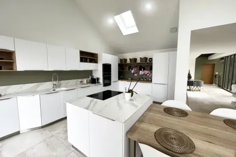 Cuisine moderne avec îlot central en marbre blanc et bois. Éclairage naturel par puits de lumière.