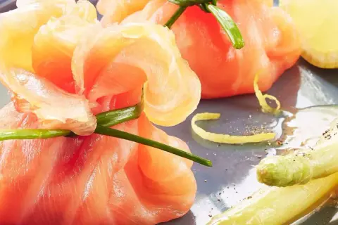 Une délicieuse entrée froide : des fagots d'asperges et de saumon fumé, ornés d'une touche de citron et de ciboule.