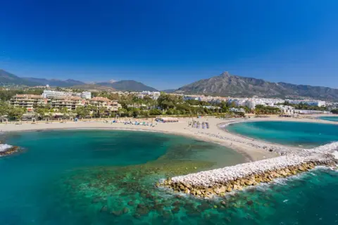 Piękne plaże i turkusowe morze w Puerto Banús, z górami w tle.