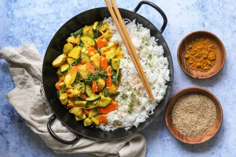 Ein leckeres Curry Geschnetzeltes Rezept mit Reis, Zucchini und Karotten, garniert mit Sesam und Kräutern.