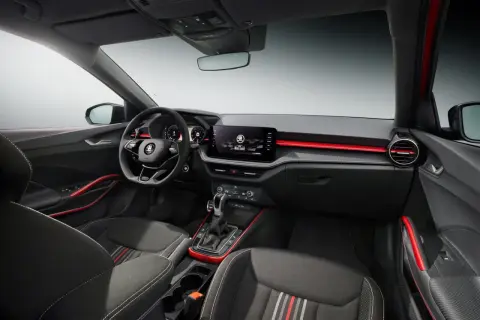 Interni sportivi della Skoda Fabia Montecarlo con sedili in tessuto, volante multifunzione e display centrale. Dettagli rossi accentuano l'abitacolo.