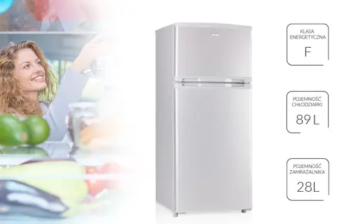 Uśmiechnięta kobieta sięga po jedzenie do lodówki MPM. Klasa energetyczna F, pojemność chłodziarki 89L, zamrażarki 28L.