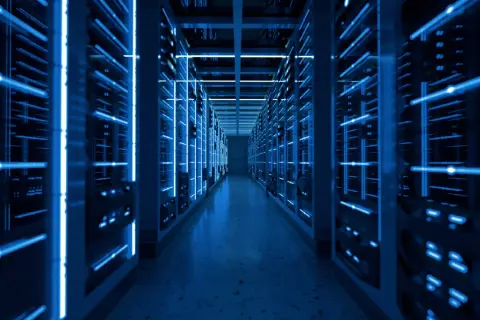 Wnętrze nowoczesnego data center z rzędami serwerów oświetlonych niebieskim światłem.