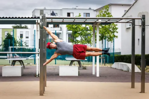 Mann hält die Flagge auf einem Calisthenics-Park. Das zeigt, was ist Calisthenics: Kraft, Balance und Körperbeherrschung.