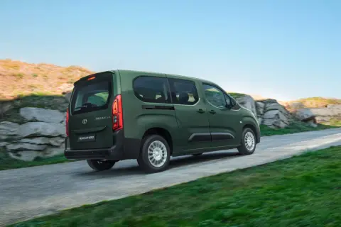 Zielony, używany Toyota Proace City Verso jedzie po krętej drodze wśród skał i zieleni.