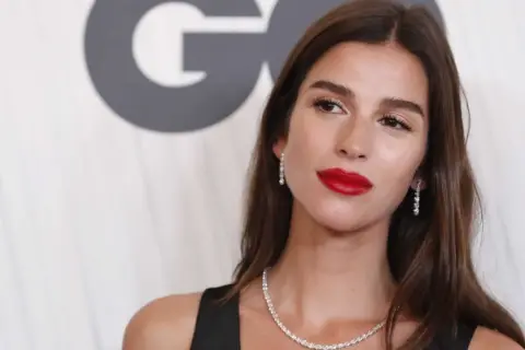 Sandra Gago, con labios rojos y joyas brillantes, posa ante un fondo con el logo de GQ.